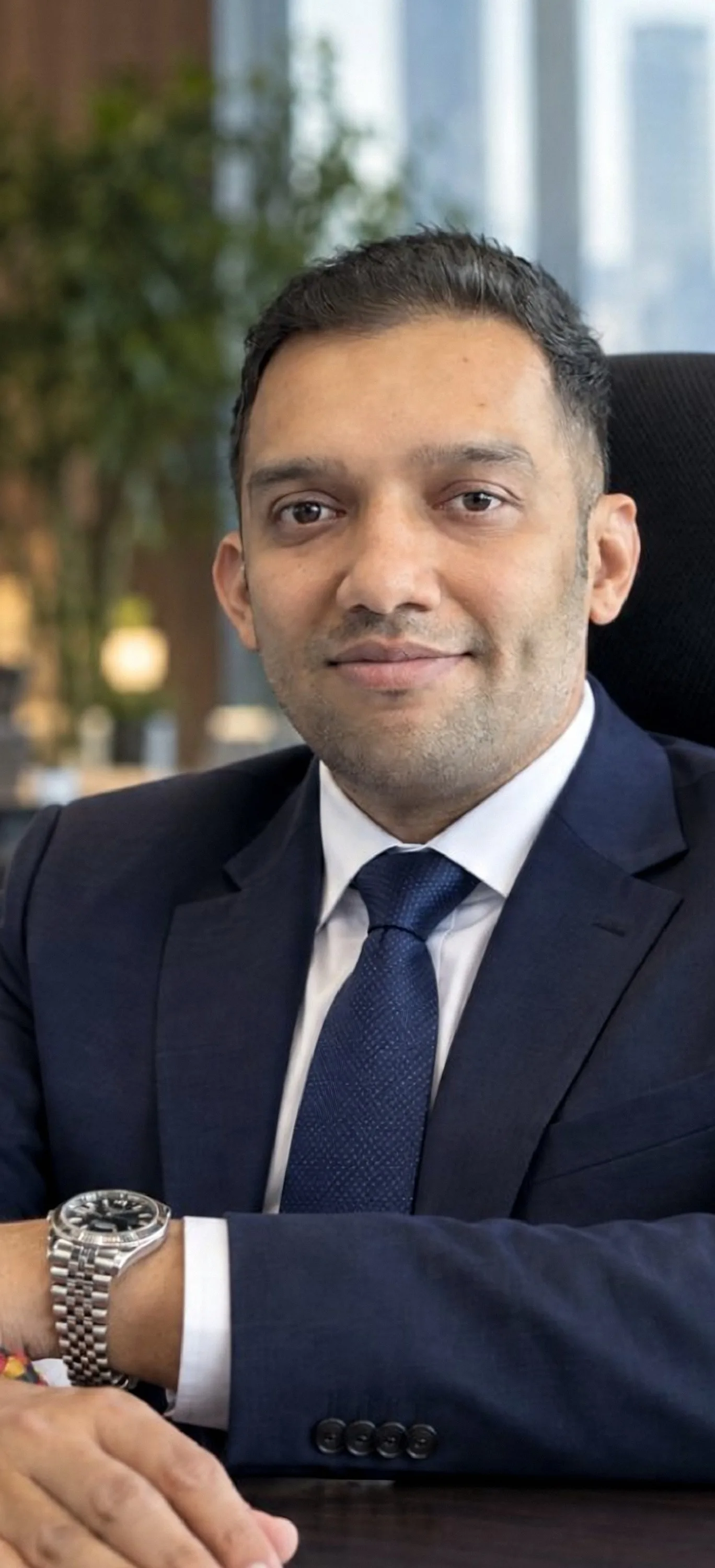 Hardik Parekh seated at his desk in a navy suit
